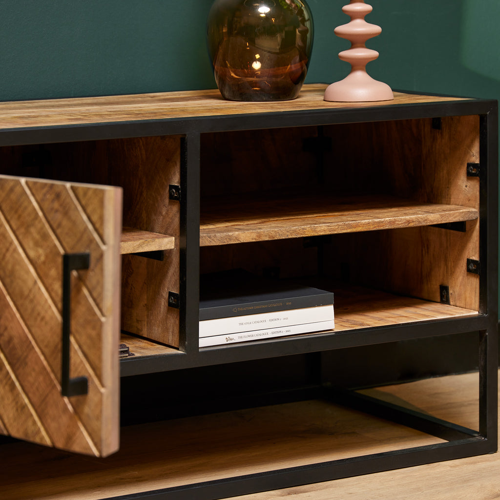 TV-Board Aloy – modernes Lowboard aus Mangoholz mit schwarzem Metallrahmen & Fischgrätmuster. Mit 1 Tür & 2 offenen Fächern. Maße: 100 x 45 x 50 cm.